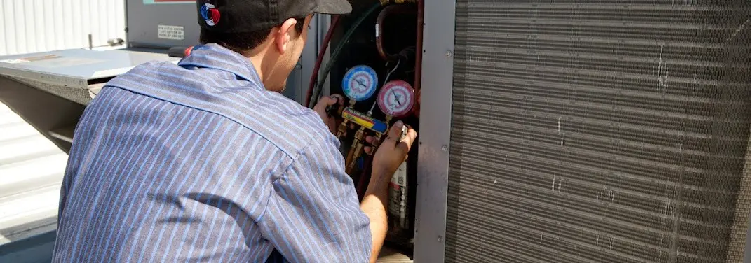 HVAC technician servicing a condenser unit in Smithfield